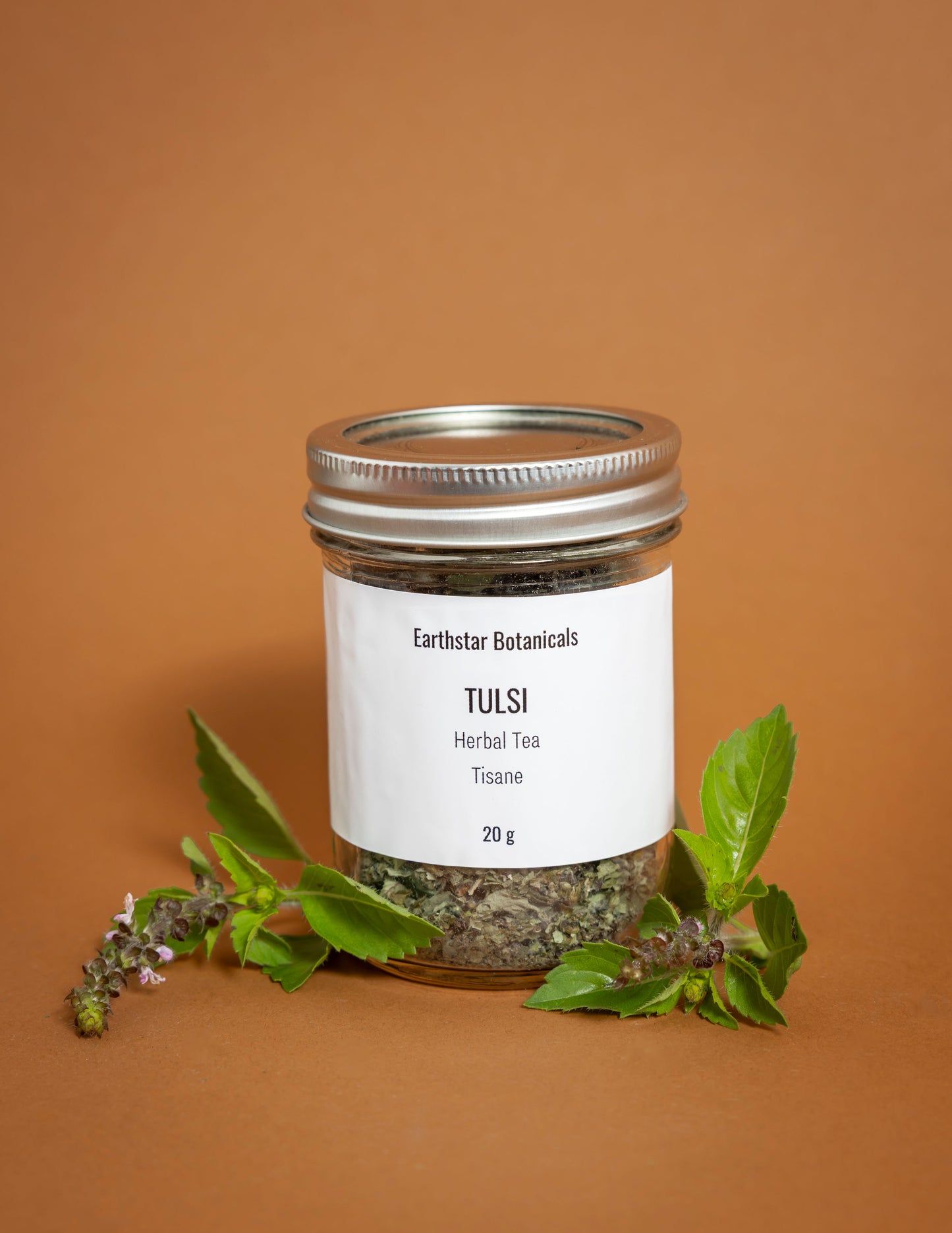 Jar of Earthstar Botanicals Tulsi Herbal Tea on an orange background