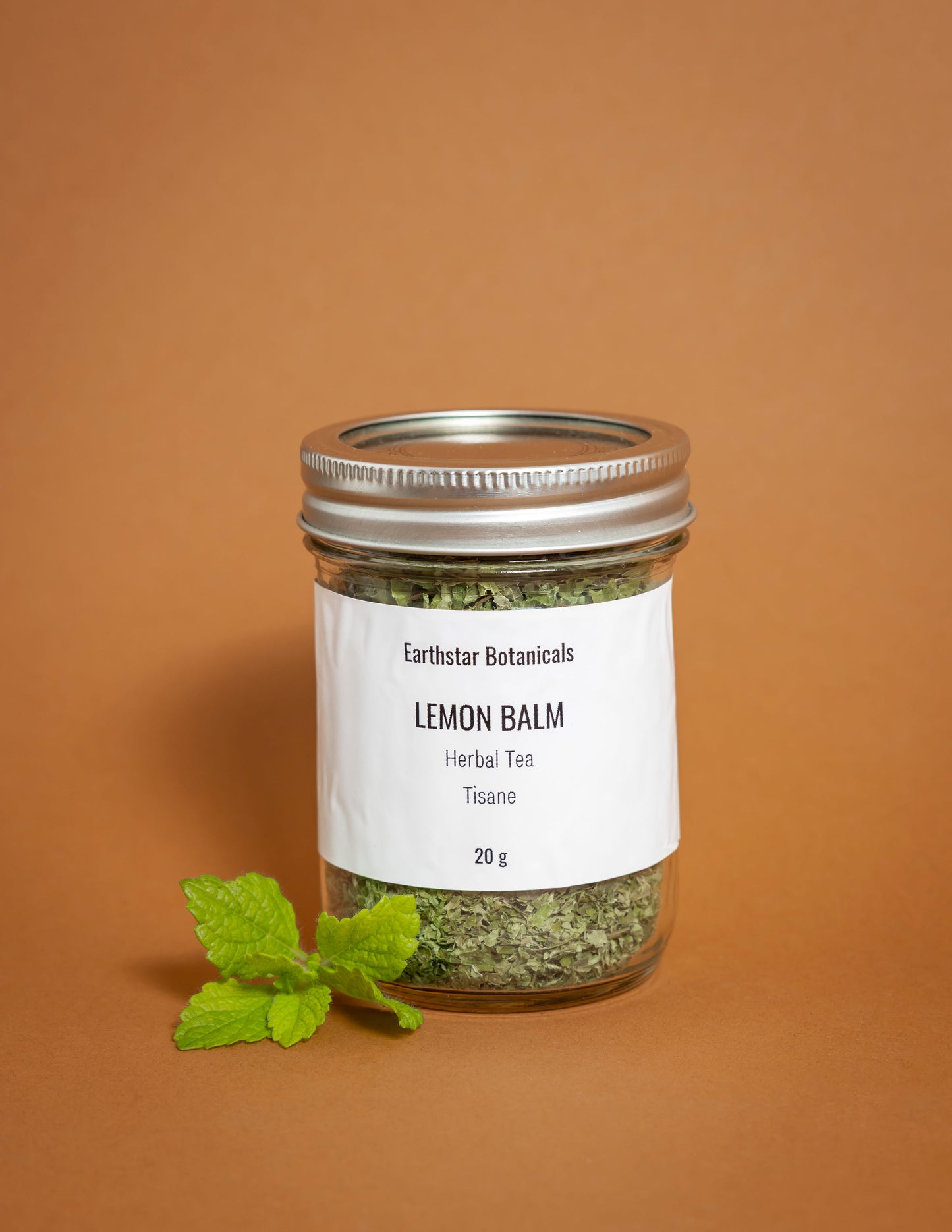 Jar of Lemon Balm herbal tea with a label on an orange background