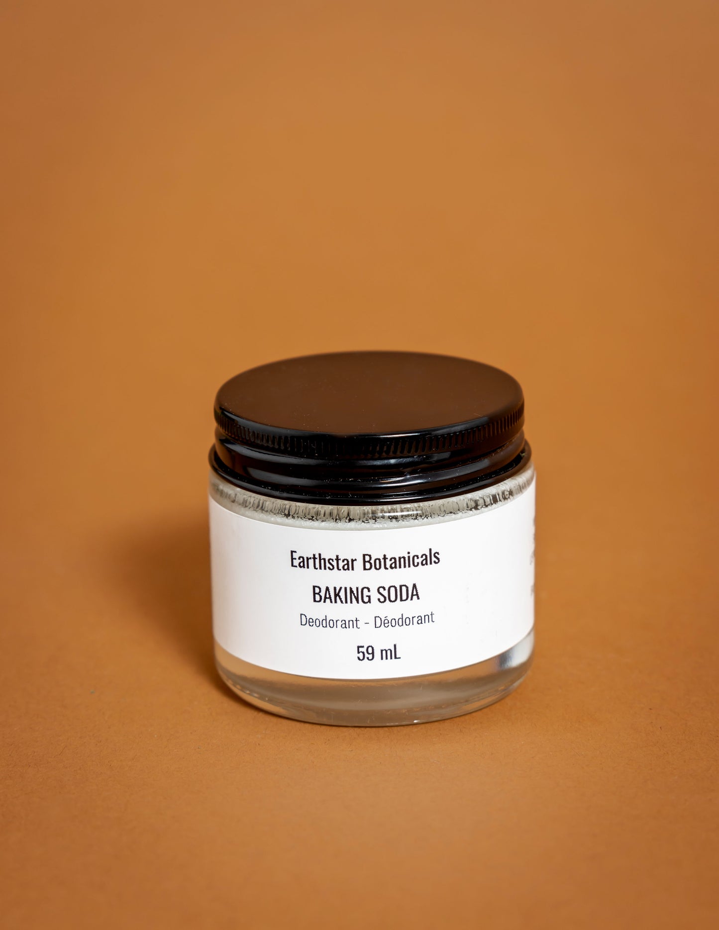 Jar of Earthstar Botanicals baking soda on an orange background