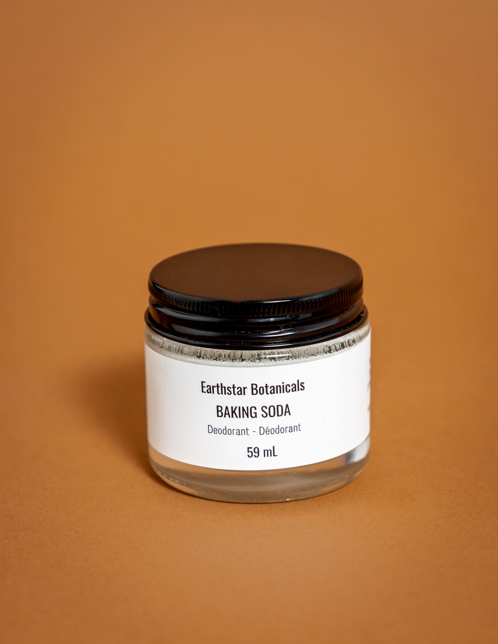 Jar of Earthstar Botanicals baking soda on an orange background