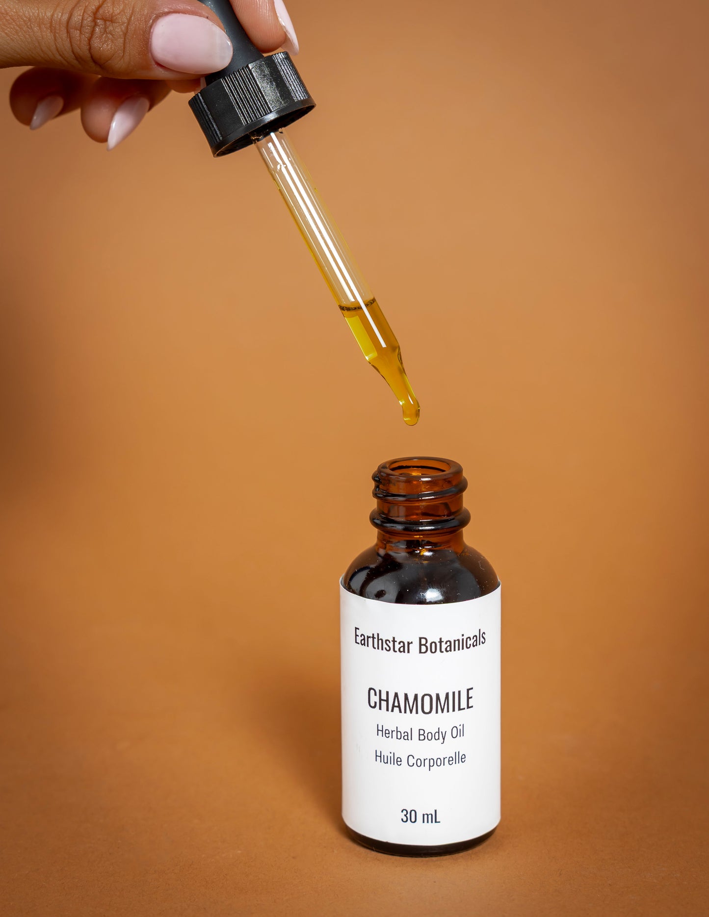 Earthstar Botanicals Chamomile Herbal Body Oil with dropper on a brown background