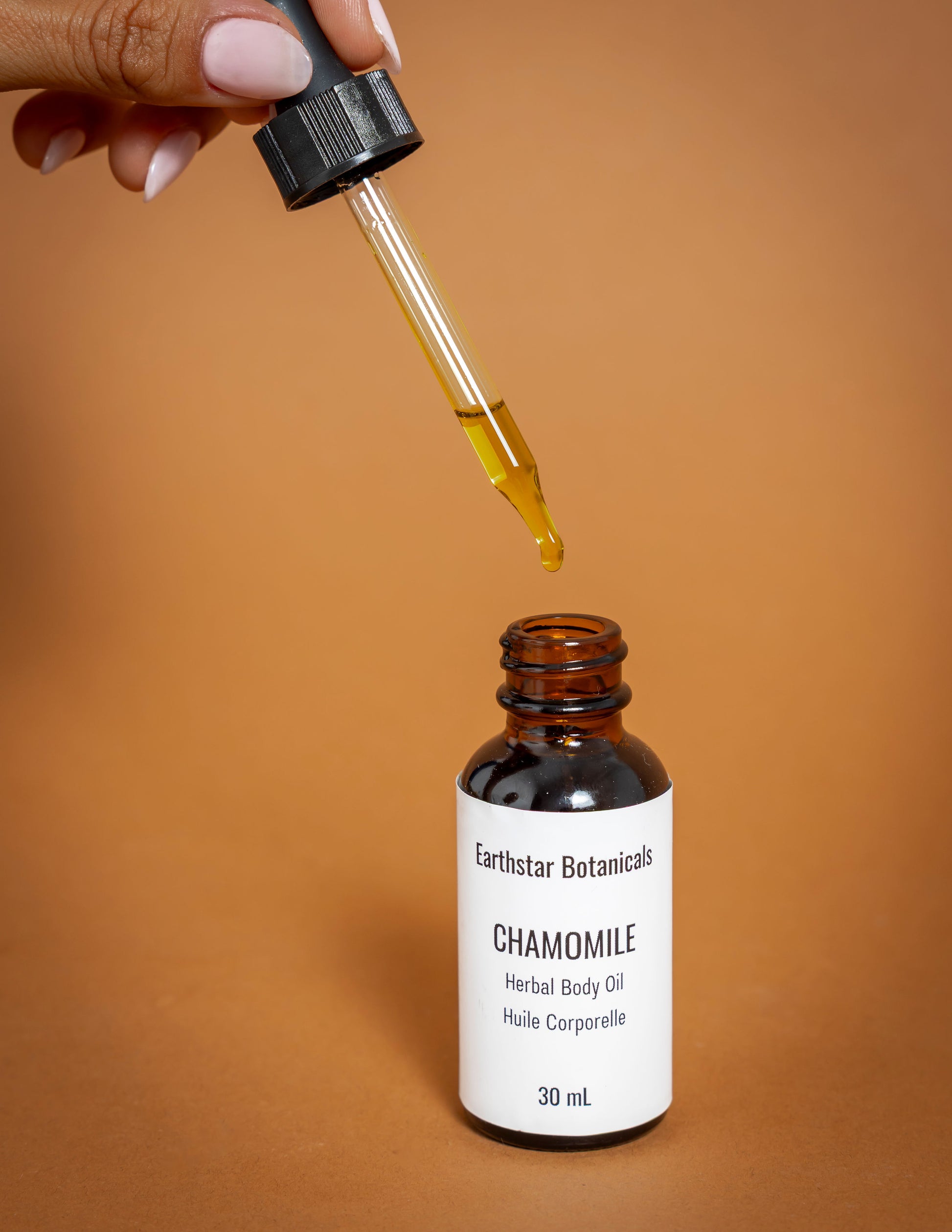 Earthstar Botanicals Chamomile Herbal Body Oil with dropper on a brown background