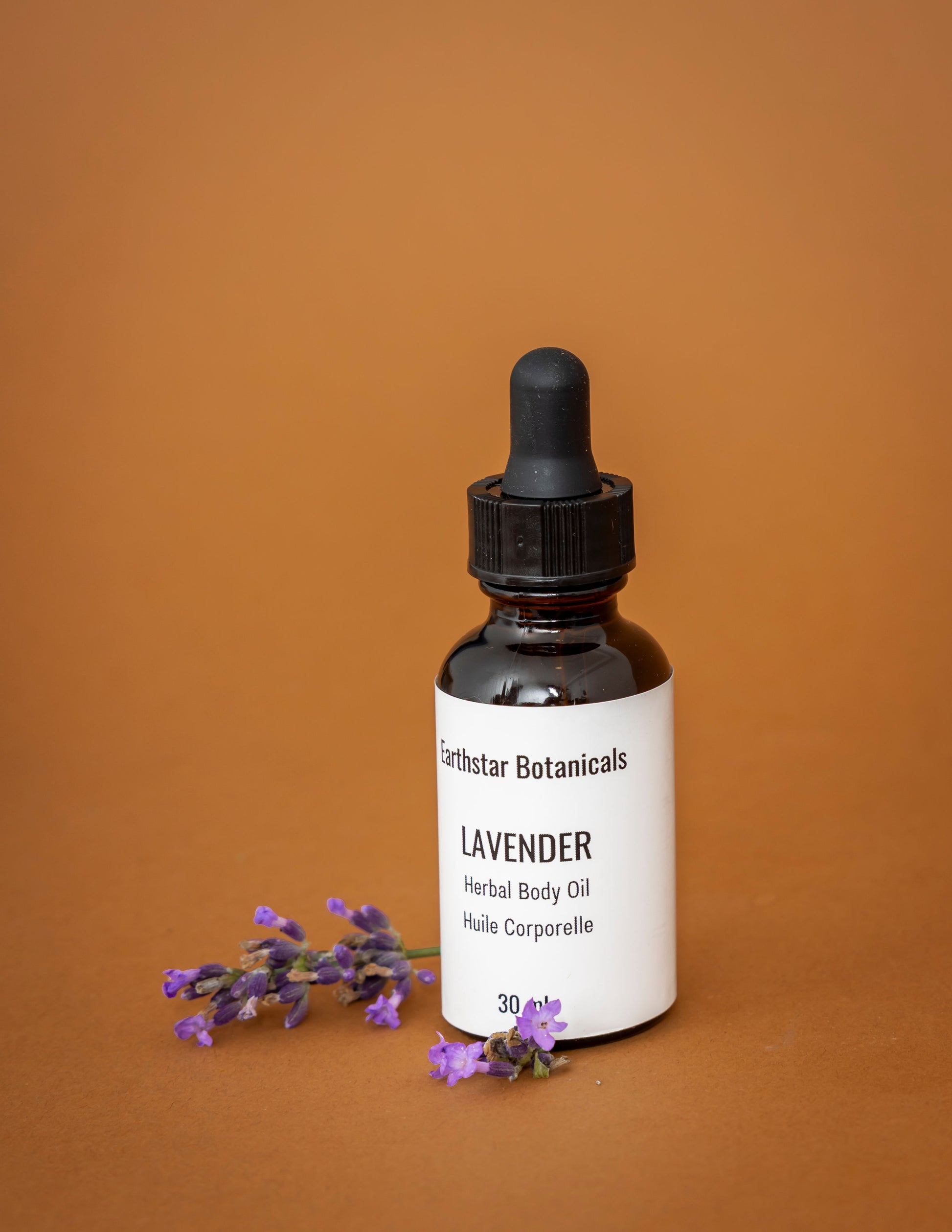 30 mL Bottle of Earthstar Botanicals Lavender Herbal Body Oil on an orange background