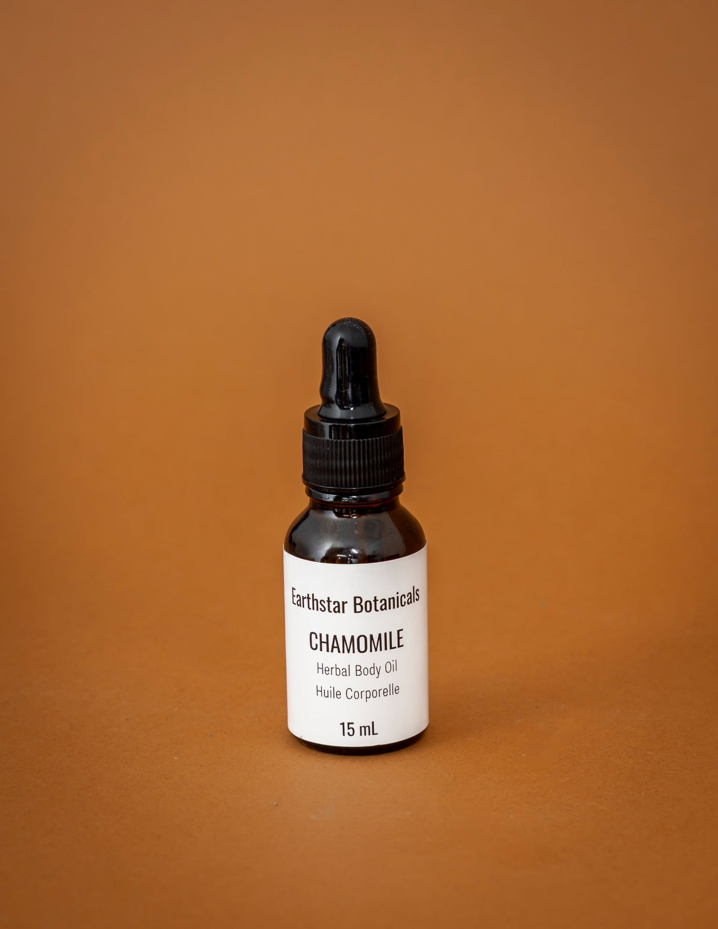 Bottle of Earthstar Botanicals Chamomile Herbal Body Oil on a brown background