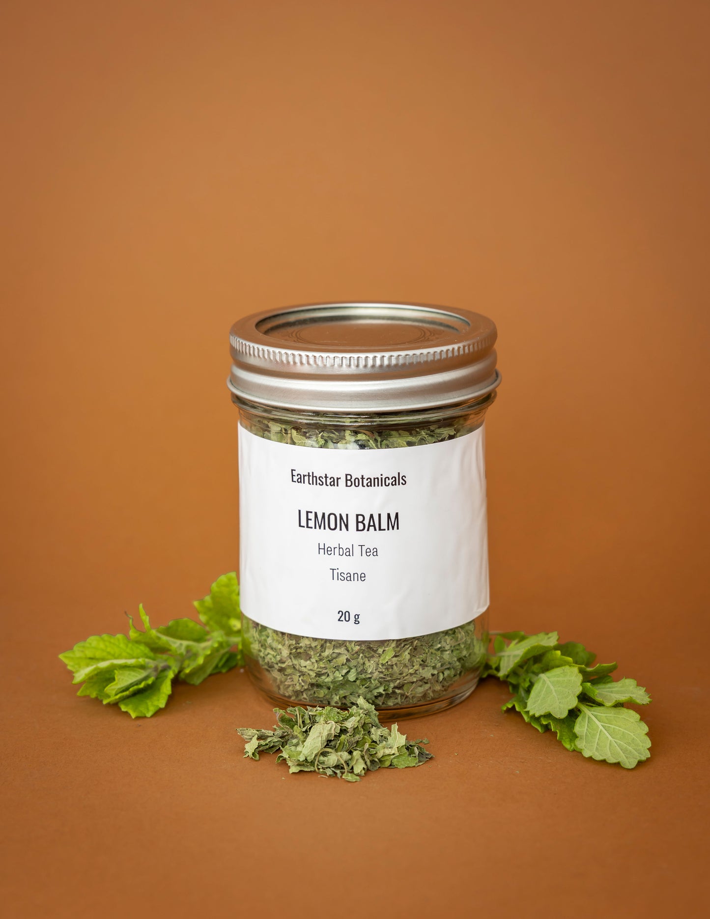 Jar of lemon balm herbal tea with a label on an orange background