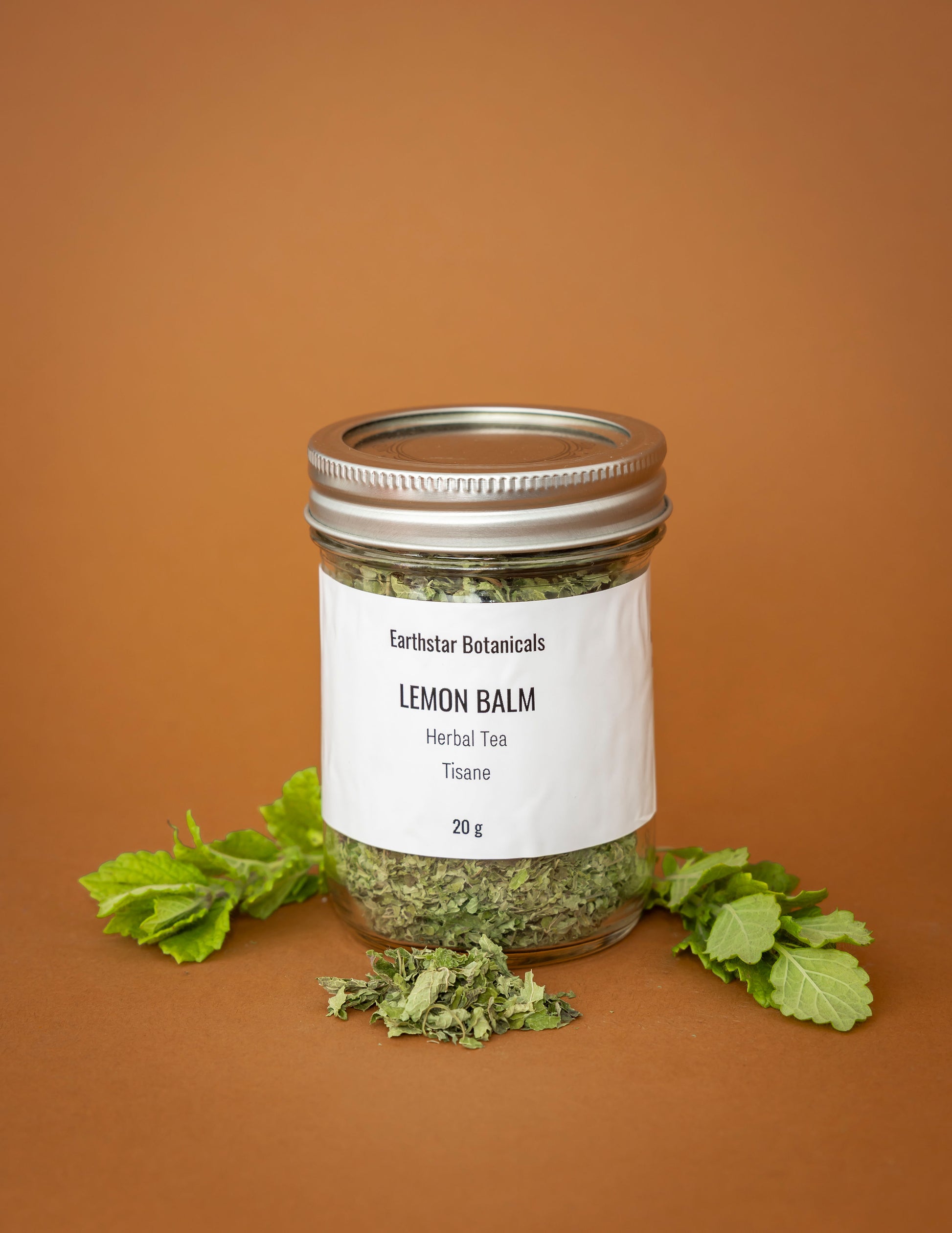 Jar of lemon balm herbal tea with a label on an orange background
