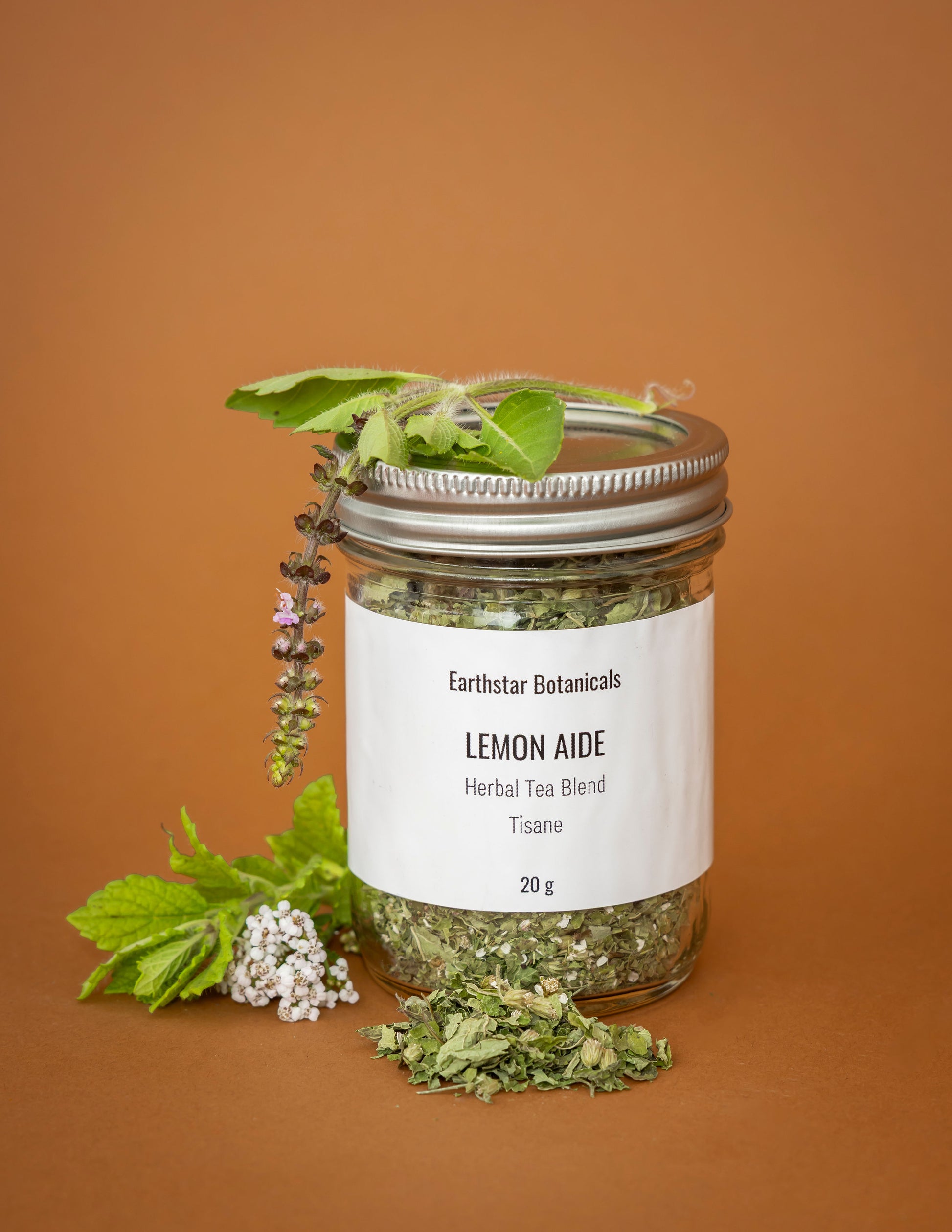 Jar of Earthstar Botanicals Lemon Aide Herbal Tea Blend on a brown background