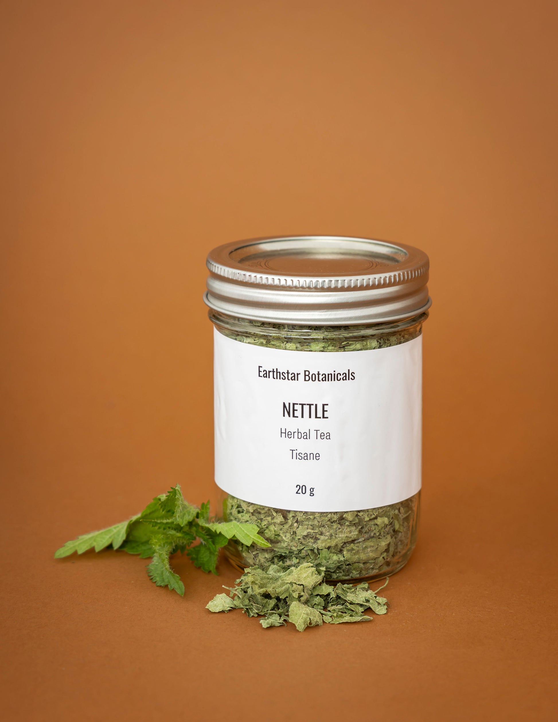 Jar of Earthstar Botanicals Nettle Herbal Tea on an orange background
